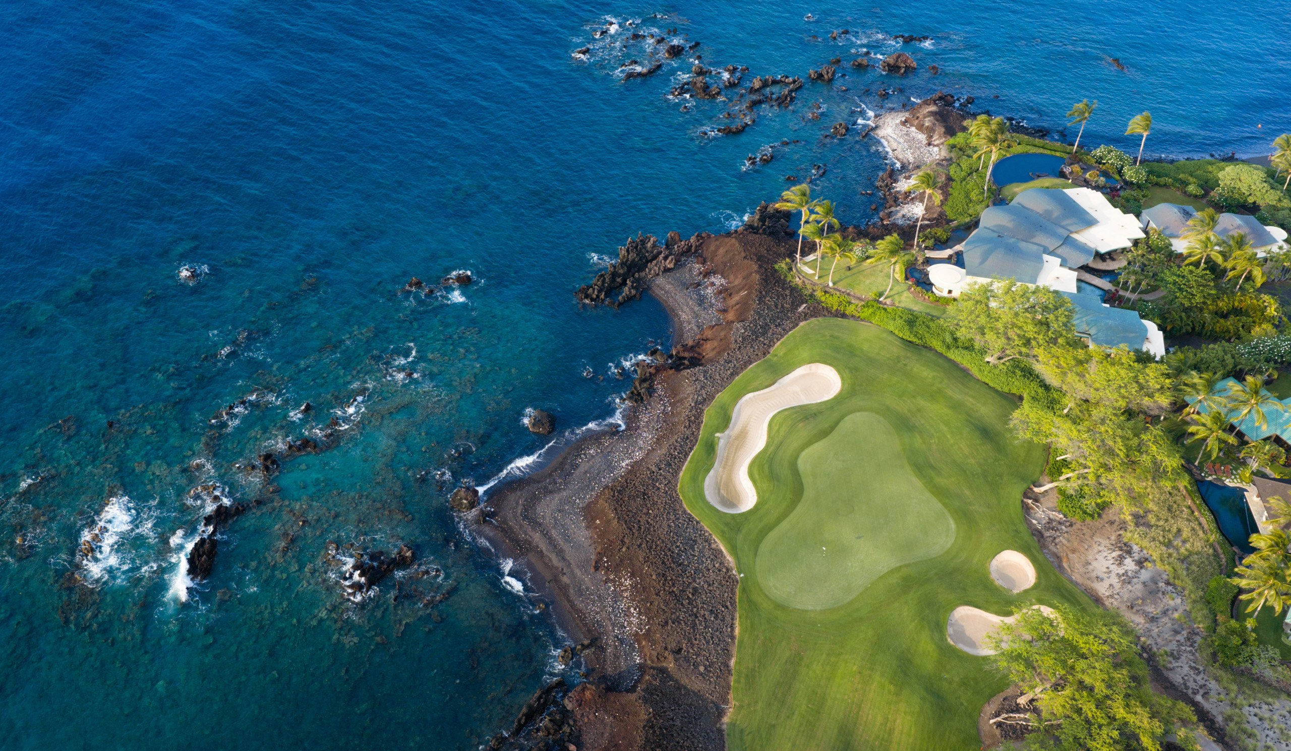 Oceanfront fairway winding along the lava coast, aerial
